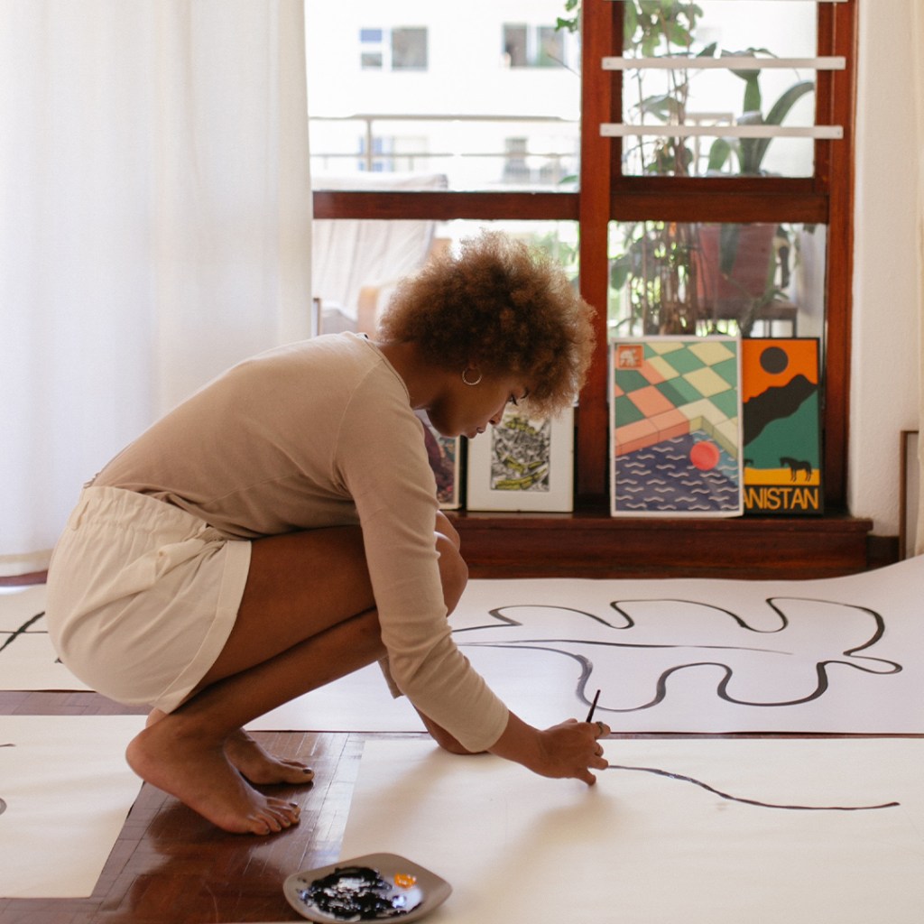Creative artist on studio floor painting on giant paper.
