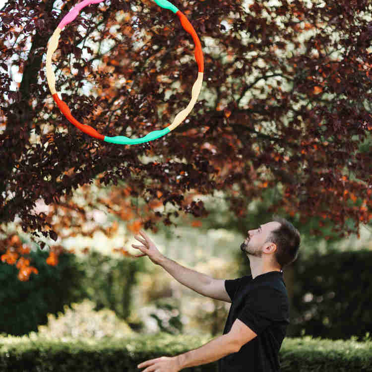 Male dancer with rainbow hula hopping, tossing in the air. 
